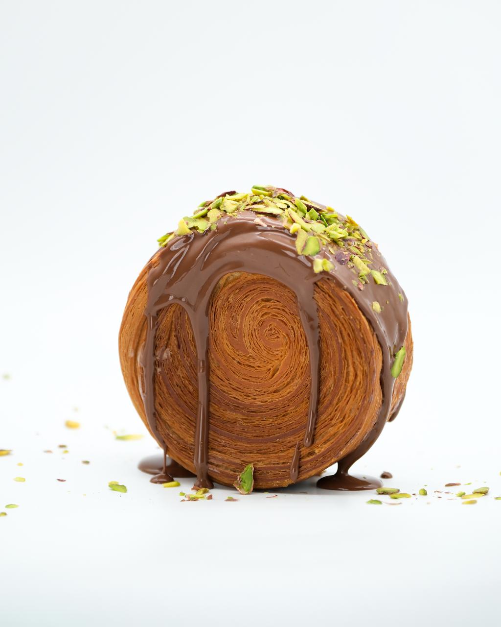 Chocolate-coated roll croissant with chopped pistachios